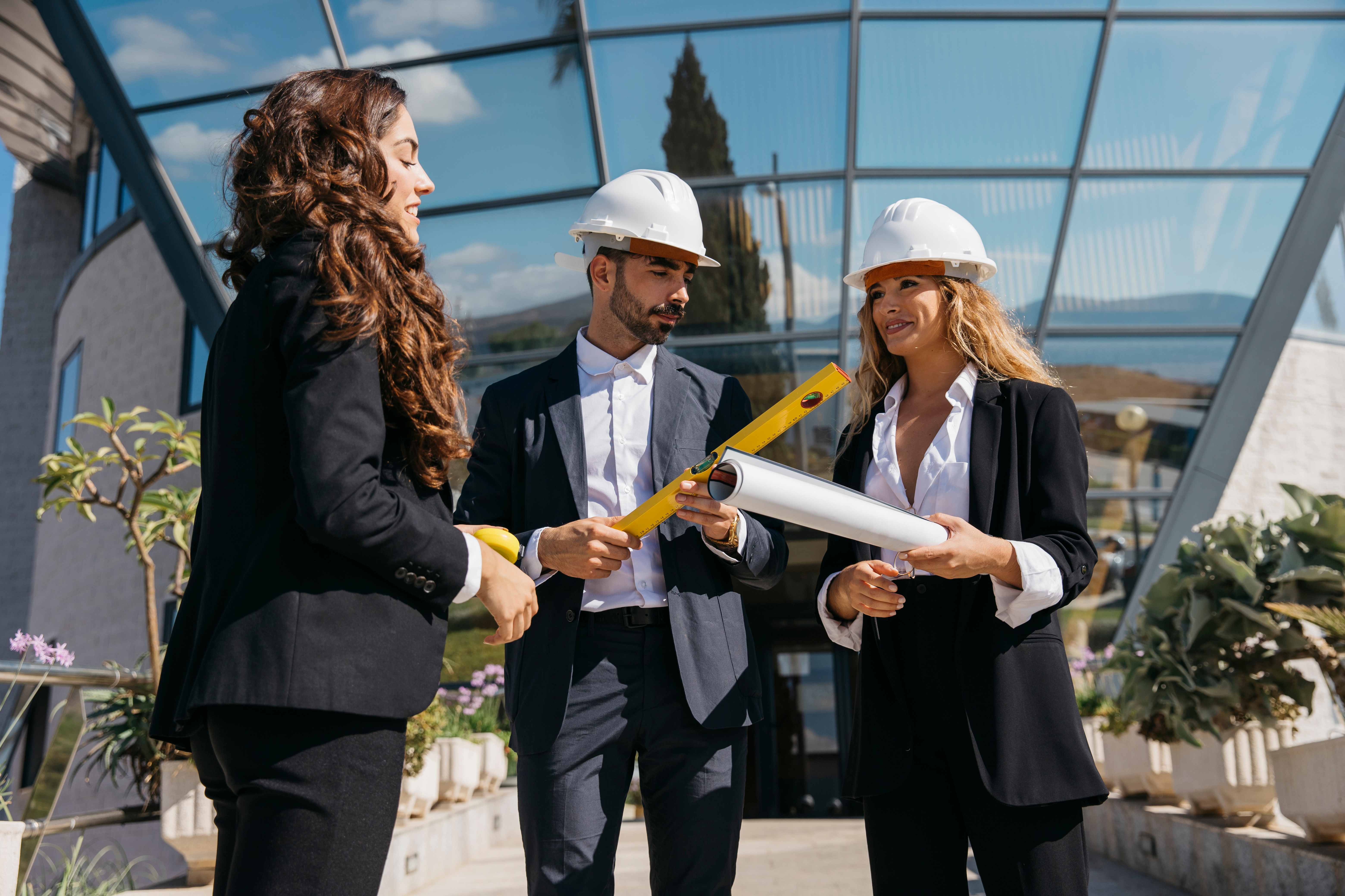 Construction management professionals reviewing blueprints and plans in front of modern building